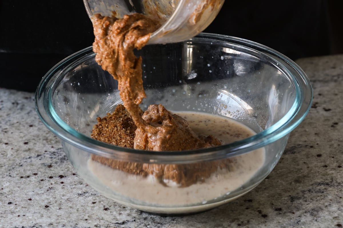 adding almond butter to the wet ingredients in a bowl