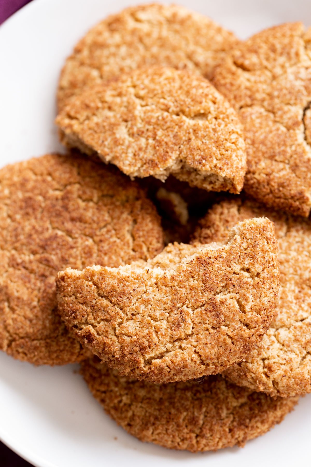 a platter with vegan glutenfree snickerdoodles with one cookie broken into half