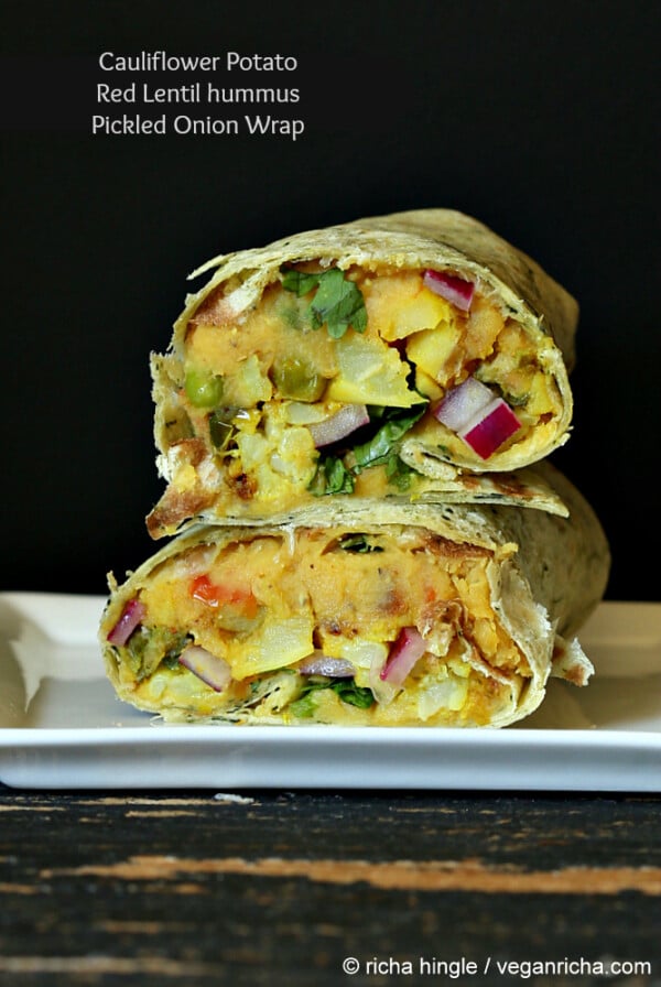 a stacked red lentil hummus wrap against a black background