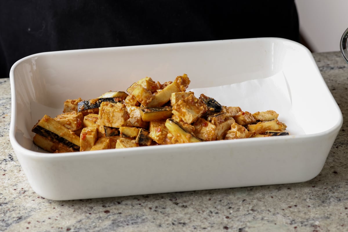 eggplant and tofu mixed with the peanut sauce spread into a lined baking pan before baking