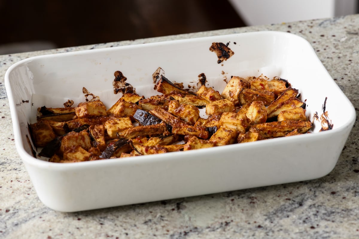 eggplant and tofu mixed with the peanut sauce spread into a lined baking pan after baking