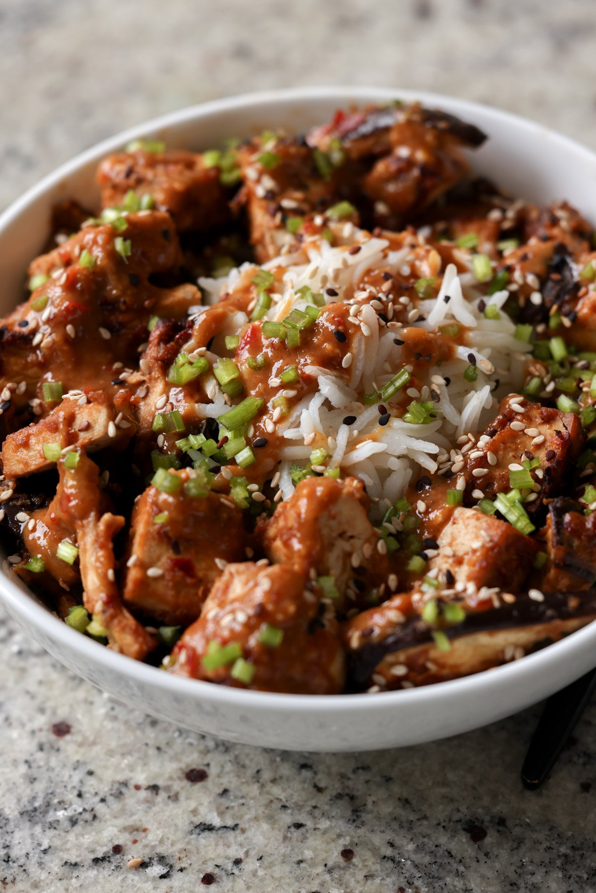 close-up of eggplant and tofu in the bowl with rice with all of the toppings