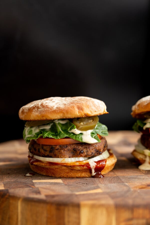 side view of a vegan black bean quinoa burger topped with vegan ranch and jalapenos