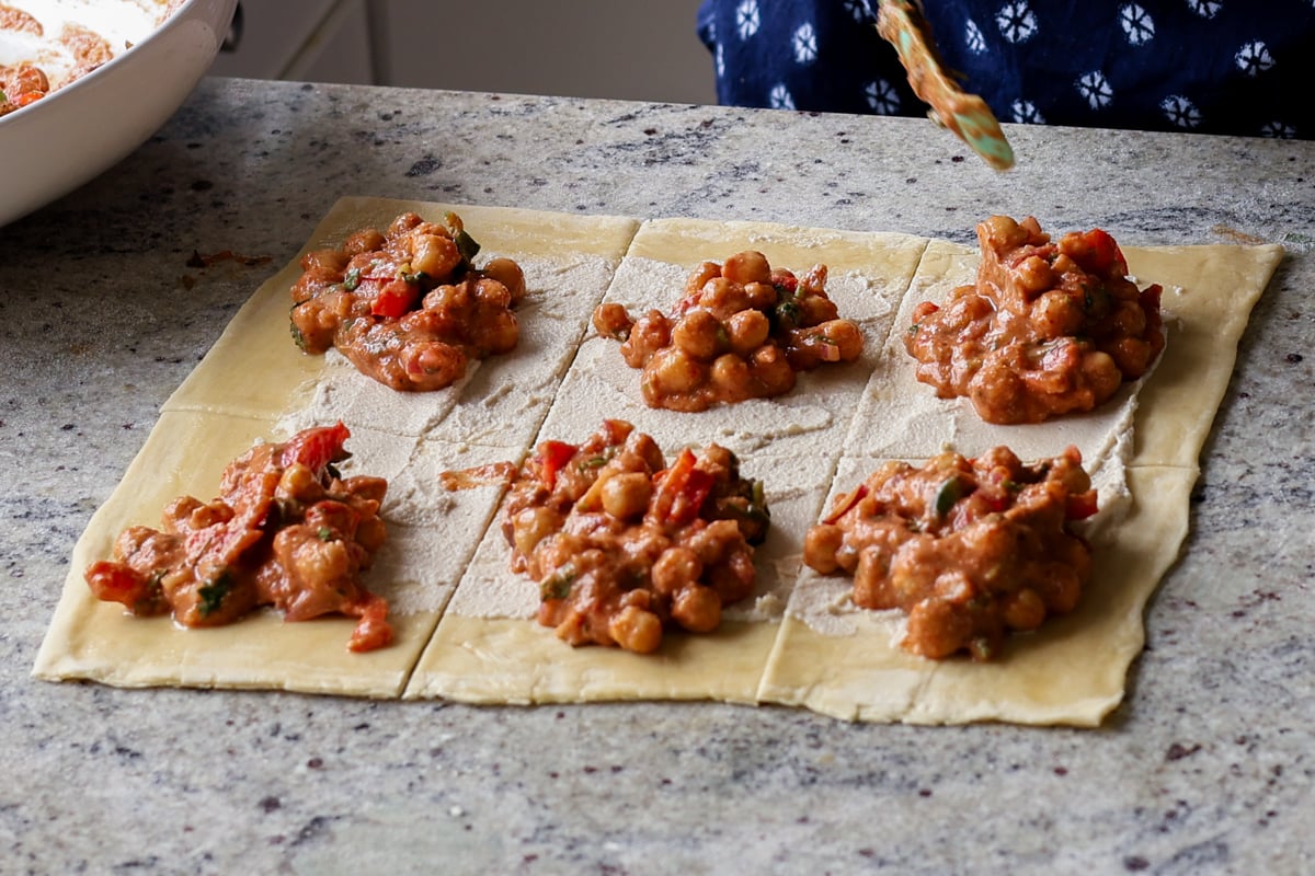 adding chickpea tikka masala mixture to the puff pastry sheet