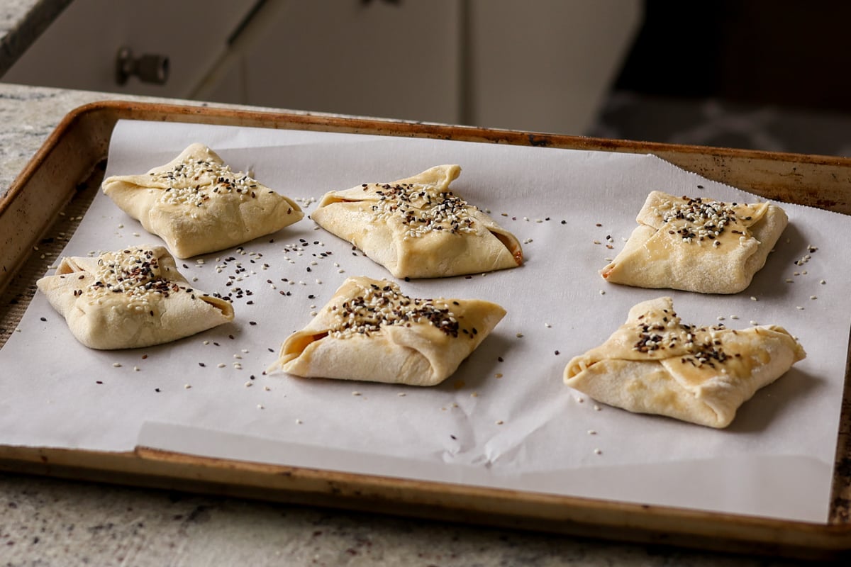 chickpea tikka masala puffs with seeds on top on the baking sheet before baking