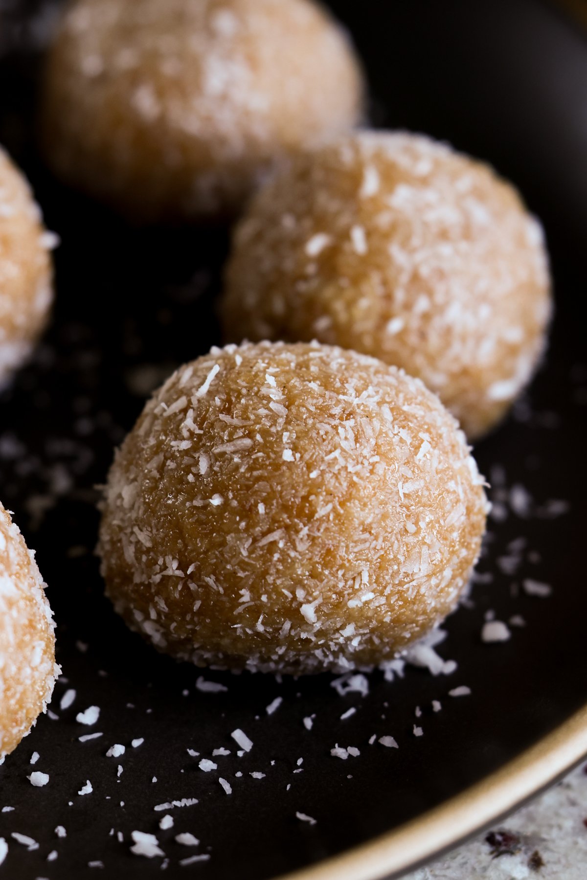 close-up of toasted coconut ladoo on a black plate