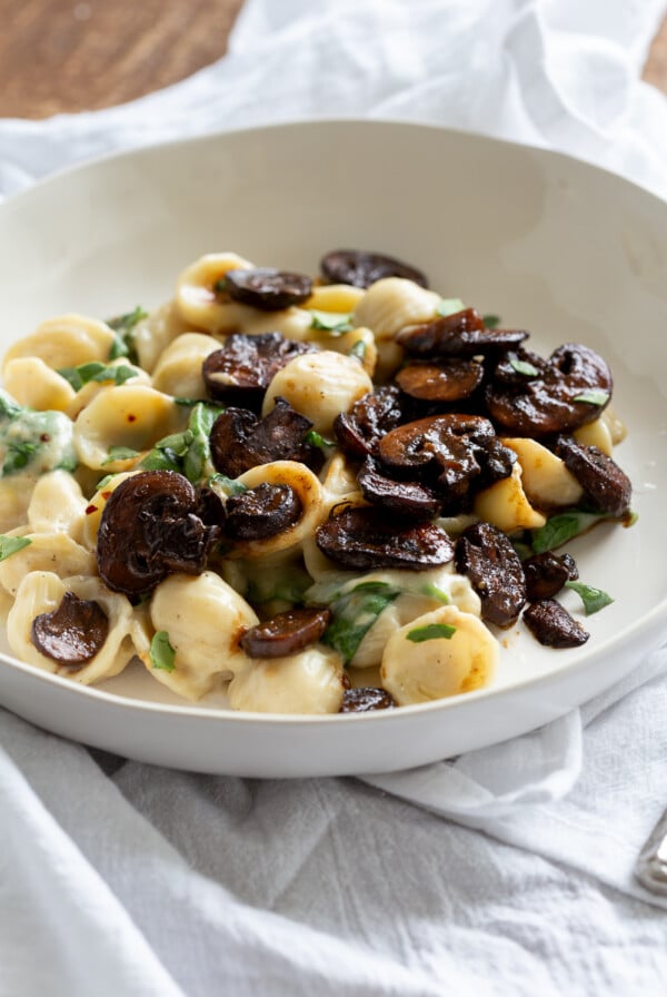 side view of a plate with vegan spinach pasta with balsamic mushrooms