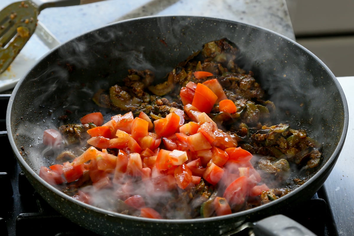 adding tomato to the cooked zucchini