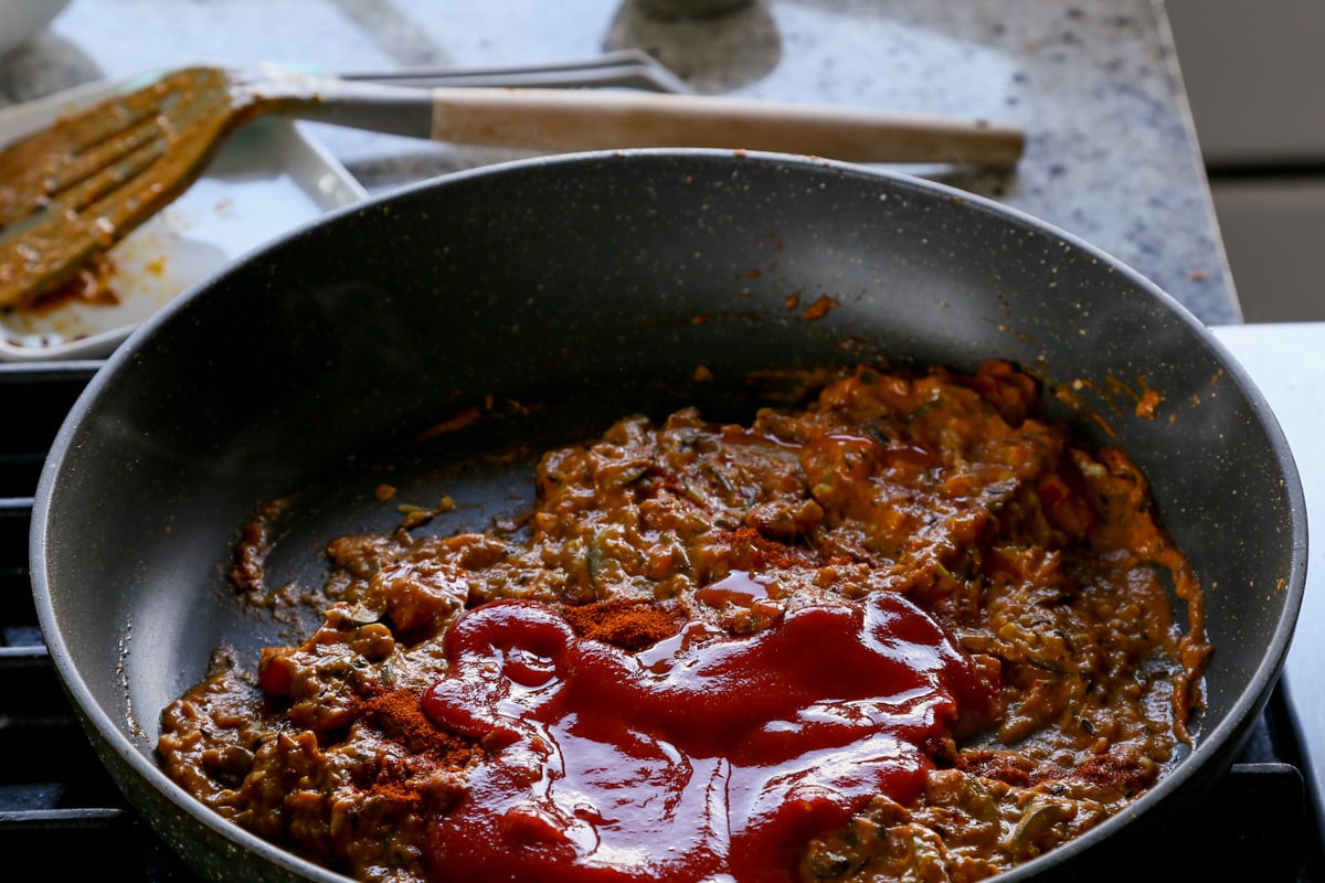 adding tomato puree to half the sauce