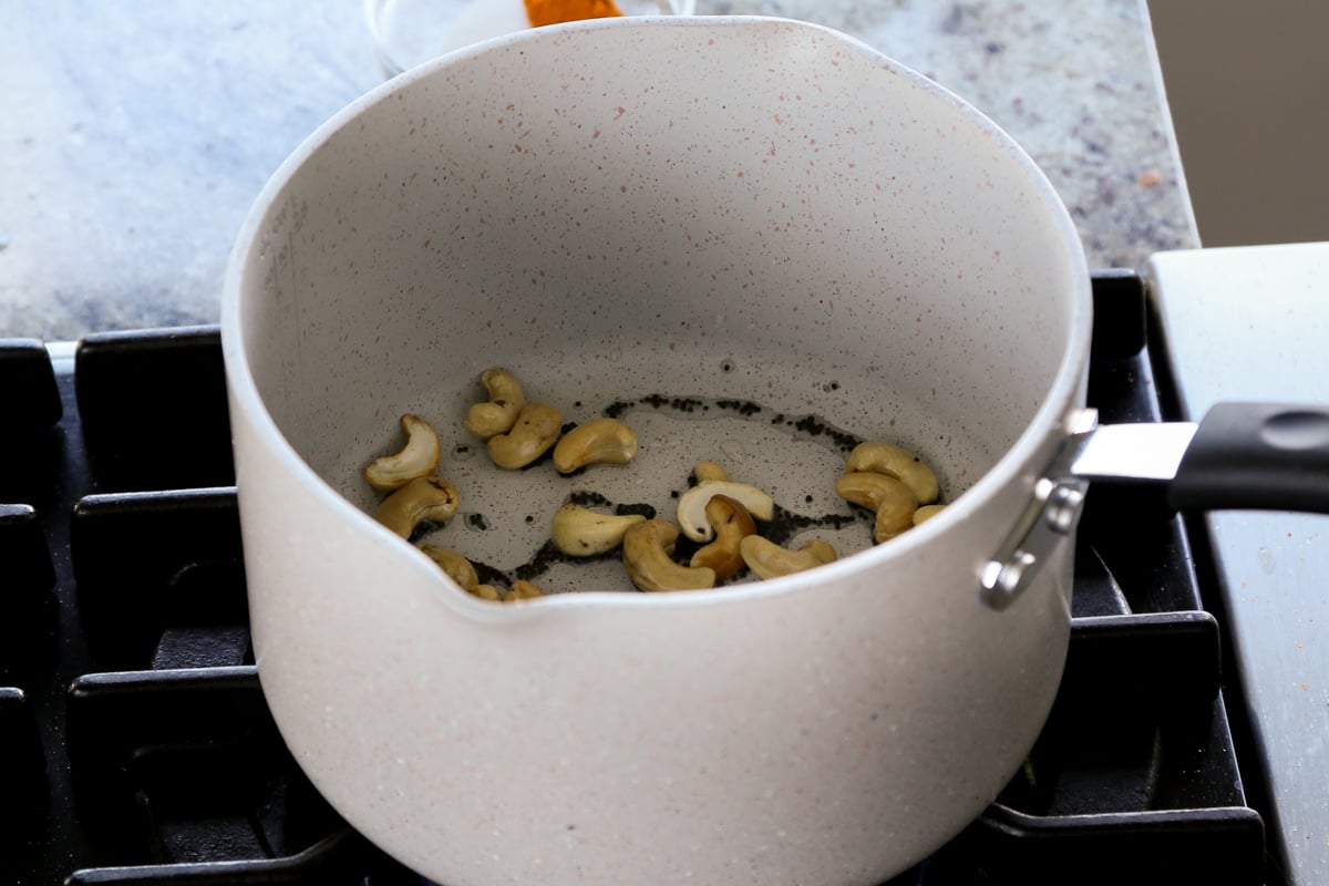 adding cashews to the pan