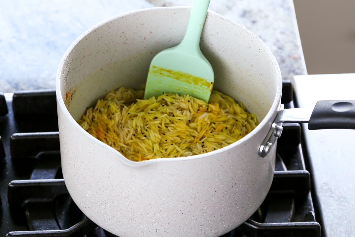 rice tossed with spices and cashews in the pan