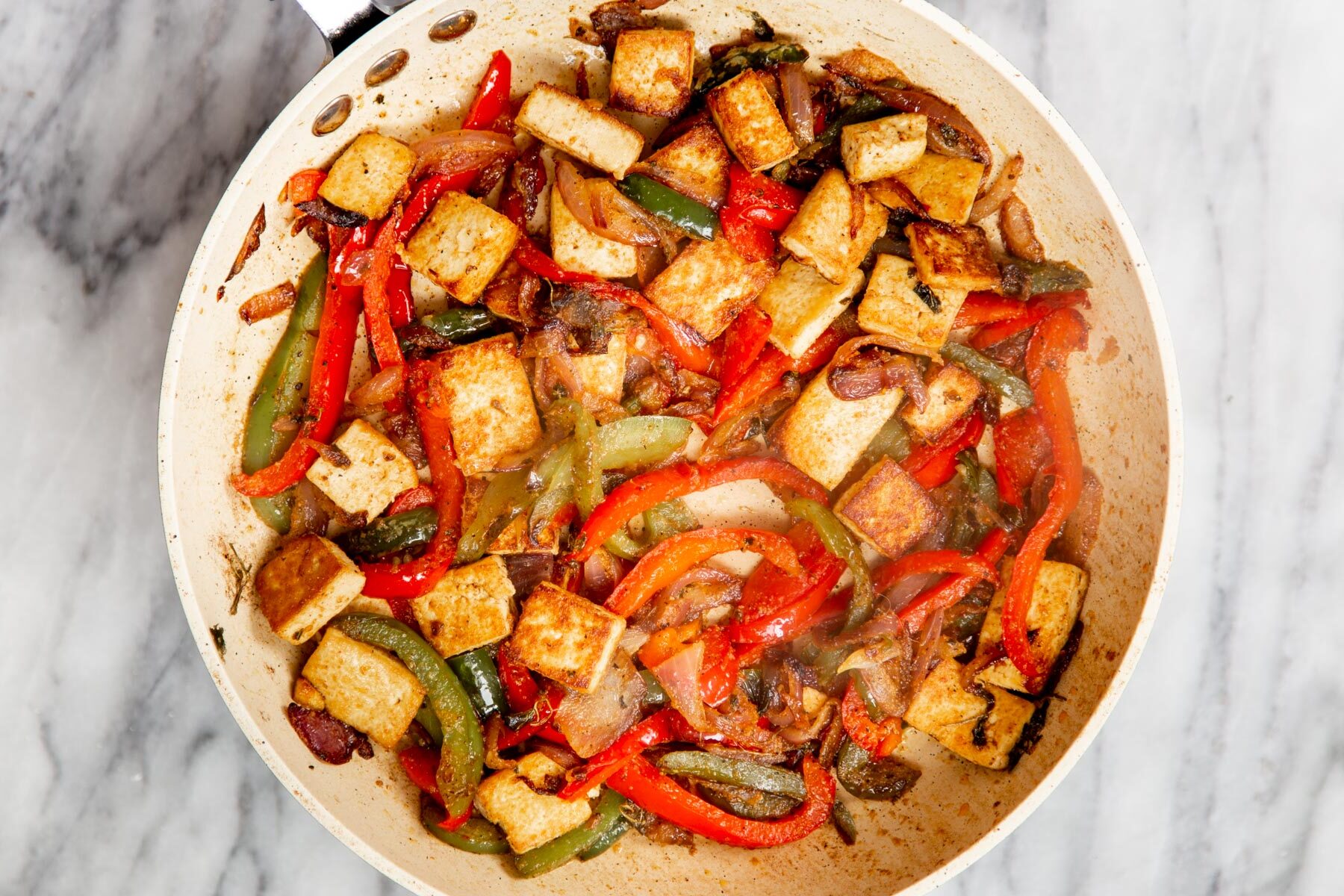 sauteed bell pepper and fried smoky tofu in a white frying pan