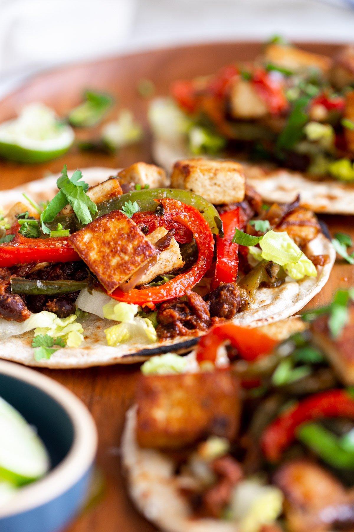 side view of three smoky tofu tacos with black beans and bell peppers