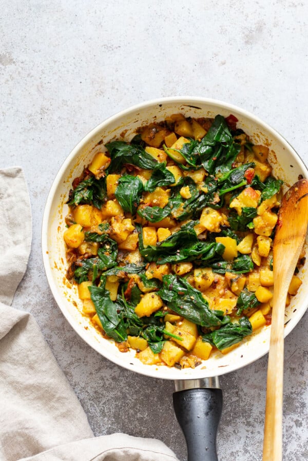 Garlic Potato Spinach Stir fry in a white skillet