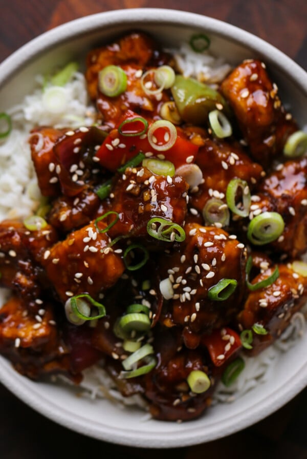 General Tso's tofu in a bowl with green onion and sesame seeds