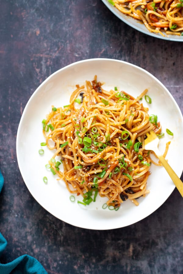 a plate of gochujang noodles sprinkled with sliced scallions