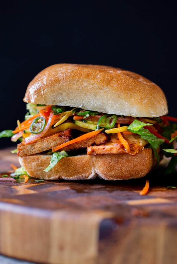 gochujang sandwich with pickled veggies on a wooden cutting board