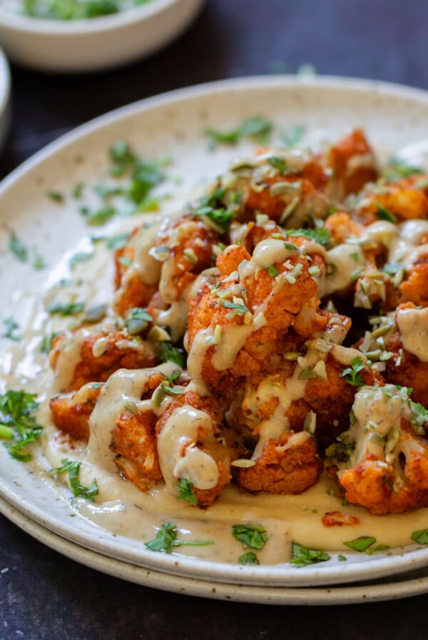 harissa cauliflower wrap tahini sauce on a bed of hummus