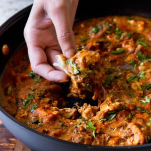 hand scooping up some Hyderabadi chicken curry on a piece of flatbread