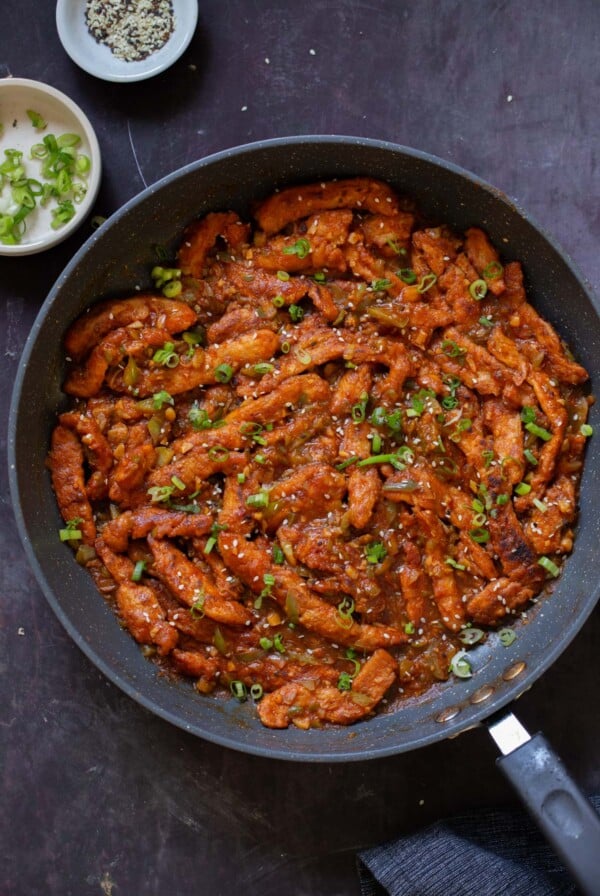 crispy Indo Chinese chicken in the pan with rice and green onions