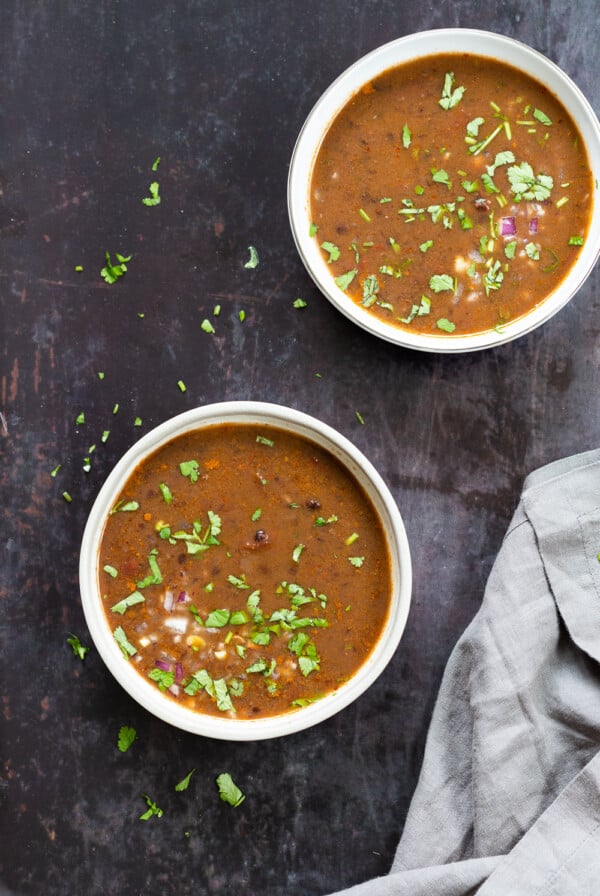 overhead shot of two bowls of vegan black bean soup against black background