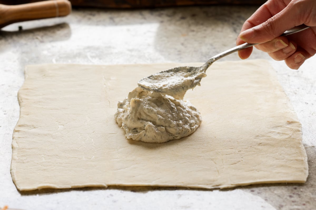 spooning jalapeño popper dip onto the puff pastry sheet