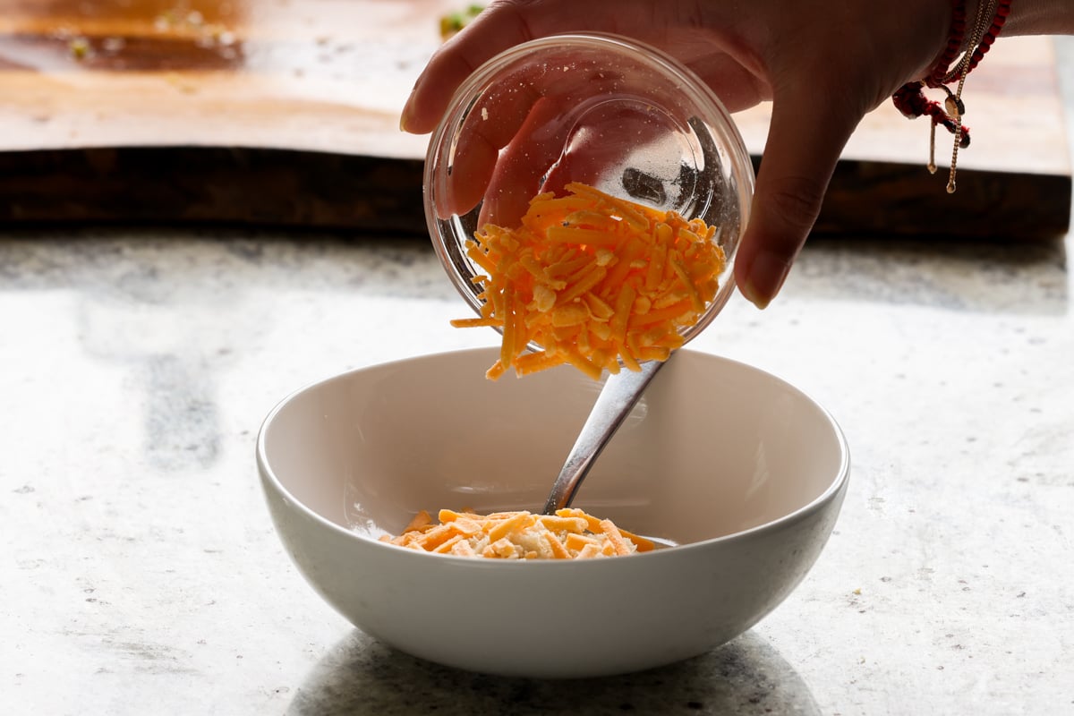 adding vegan cheddar to a bowl