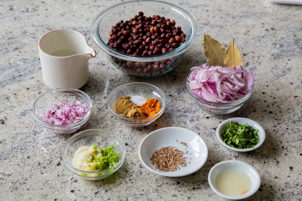 brown chickpeas, vegg, and spices in bowls on the kitchen counter