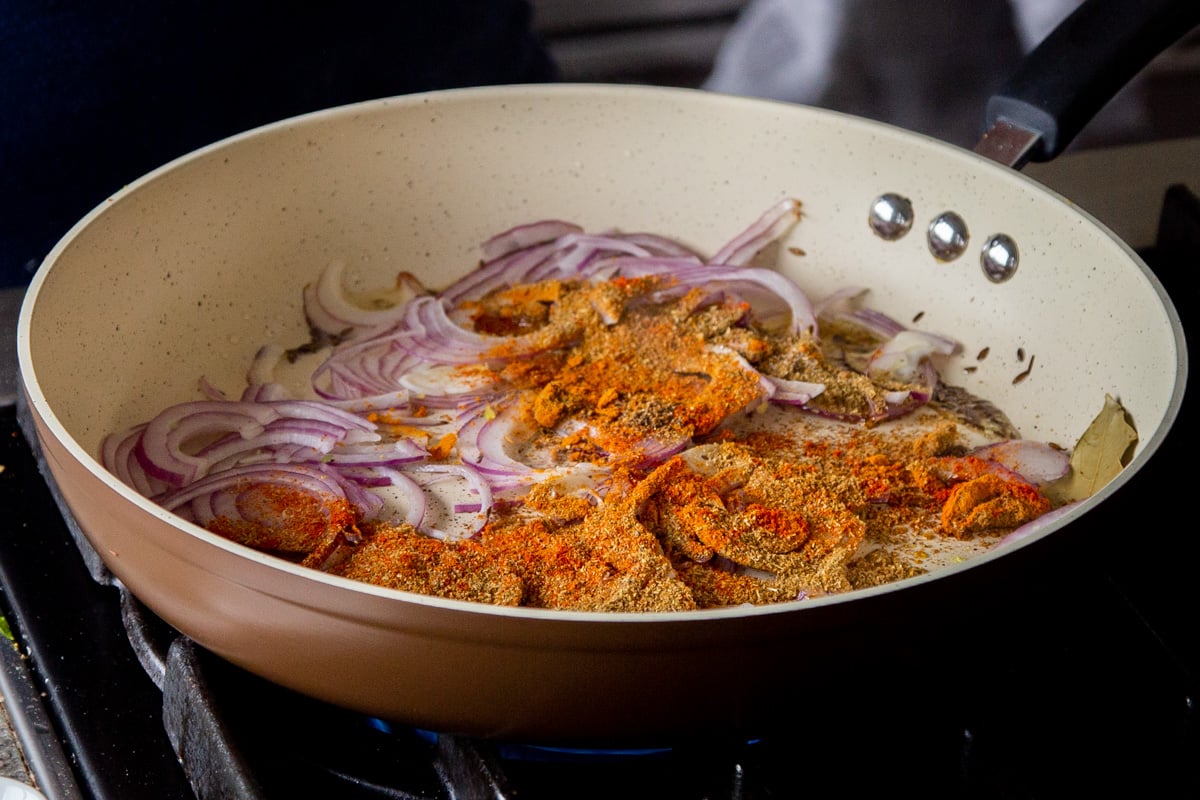 adding onion and dried spices to the frying pan