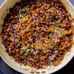 ghugni garnished with onions, cilantro, and cumin in the frying pan