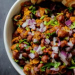 close-up of ghugni garnished with onions, cilantro, and cumin in a bowl