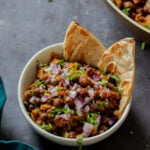 ghugni garnished with onions, cilantro, and cumin in a bowl with flatbread