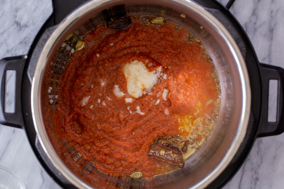 adding the tomato mixture and ginger paste to the Instant Pot