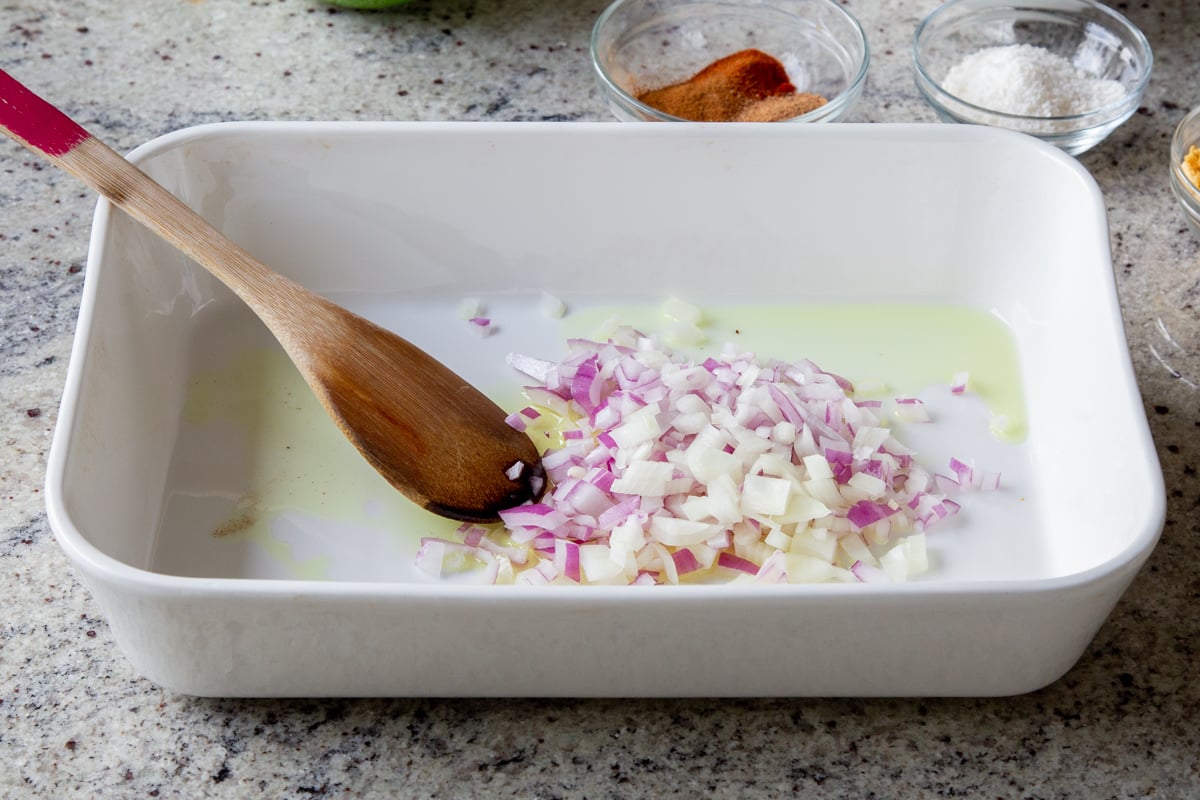 adding onion, ginger, and garlic to the baking pan