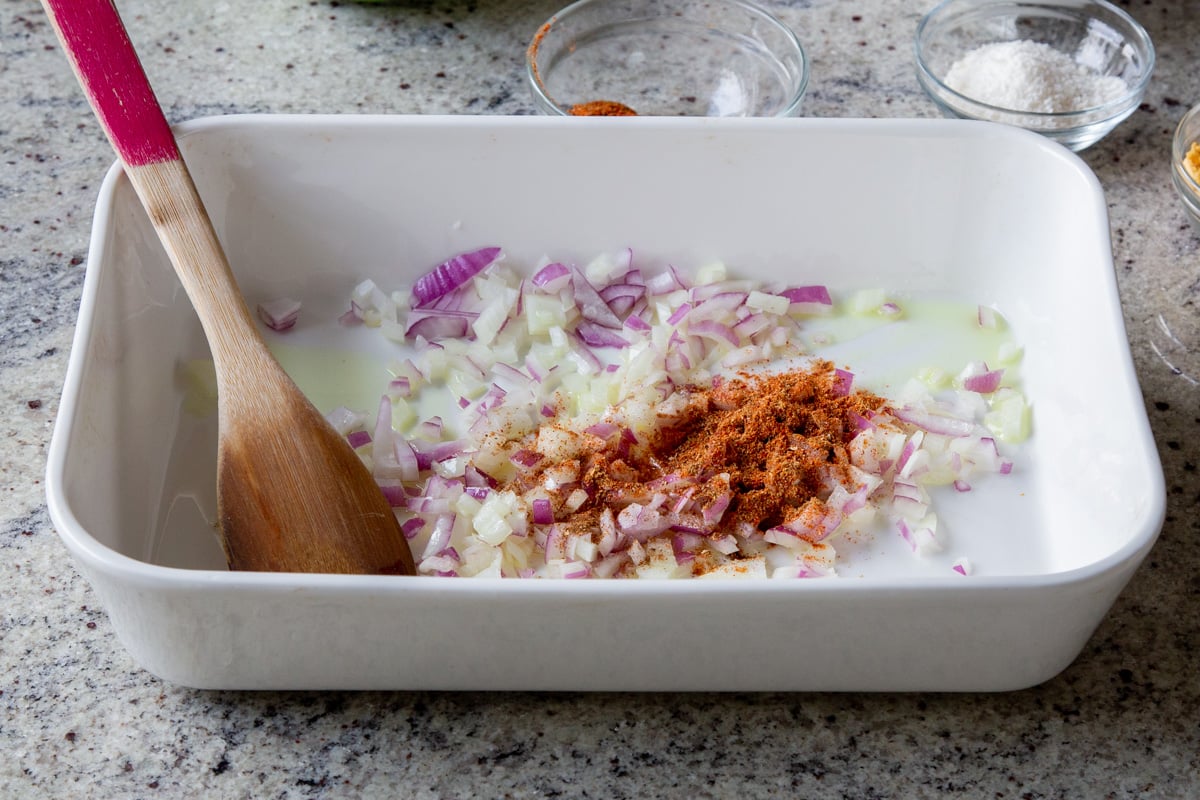 adding onion, ginger, garlic, and spices to the baking pan