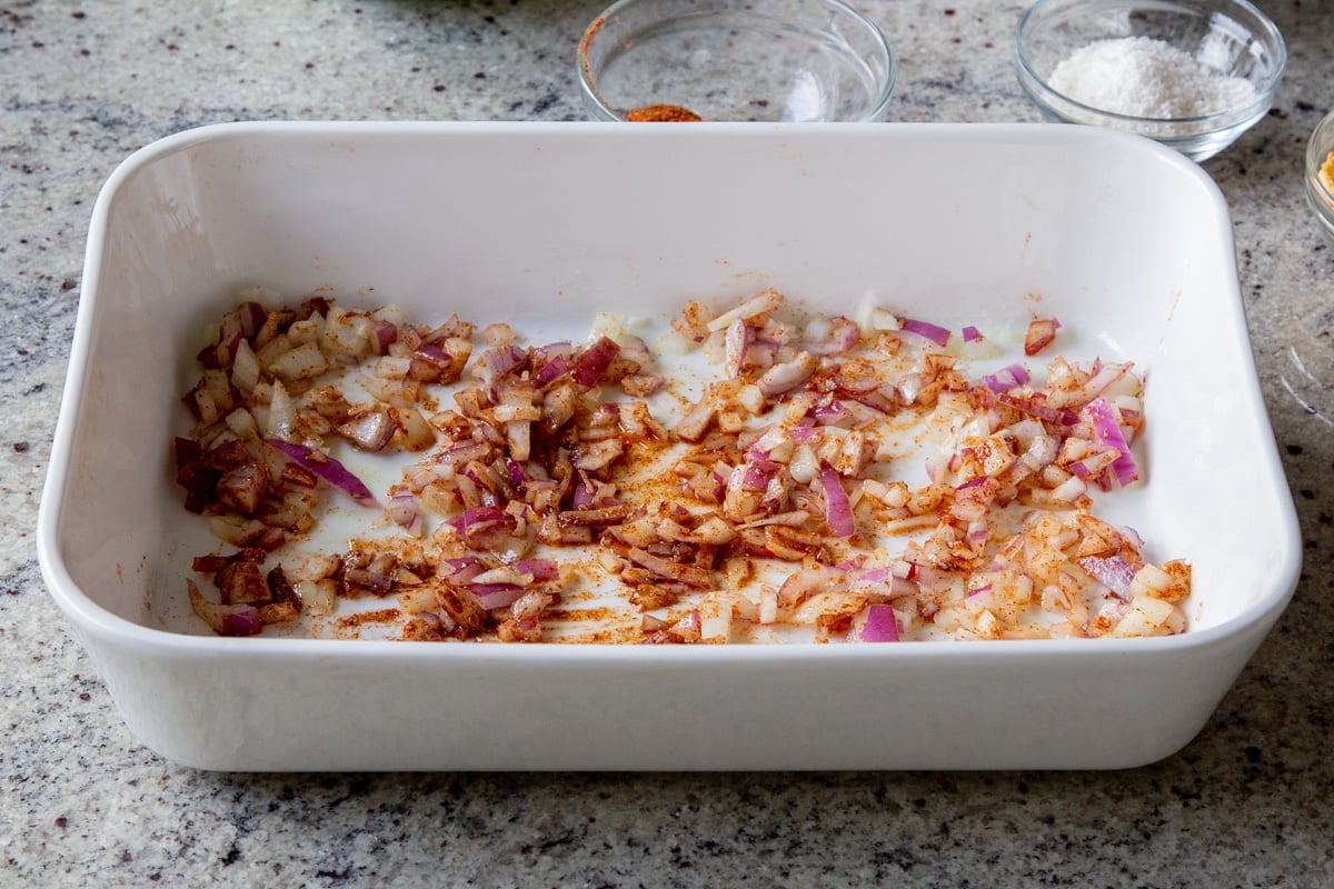 adding onion, ginger, and garlic mixed with the spices in the baking pan, before baking