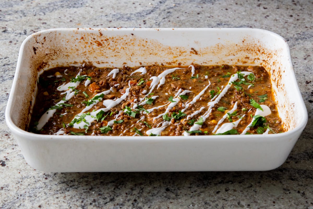 baked Konkani curry topped with coconut cream, cilantro, and pepper flakes in the baking pan