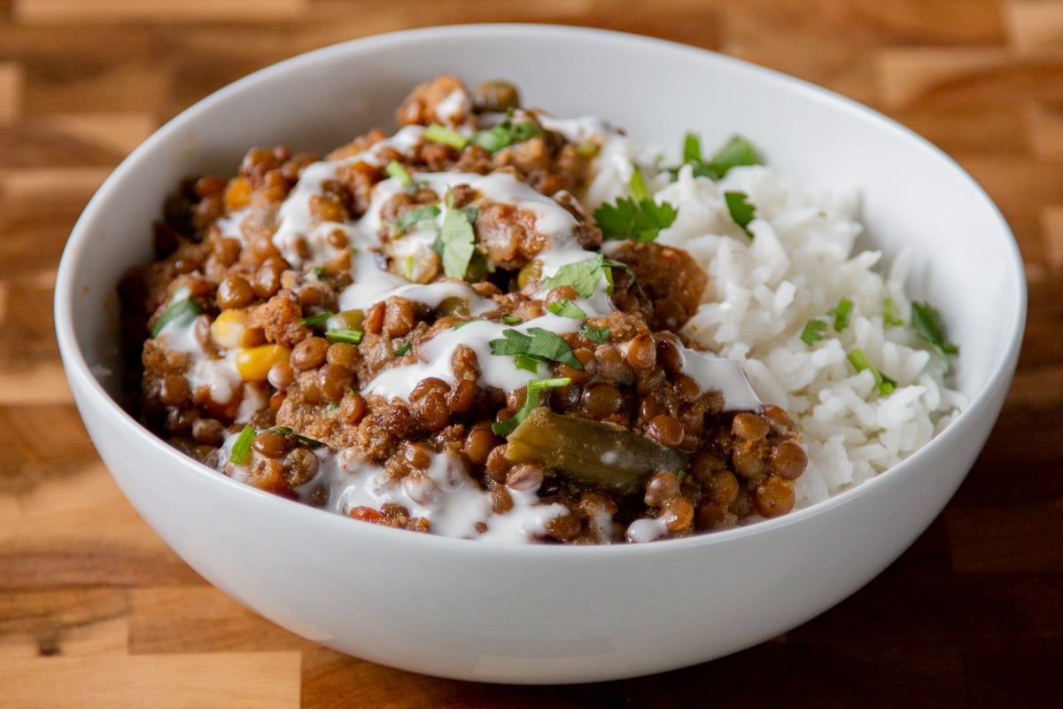 bowl of baked Konkani curry topped with coconut cream, cilantro, and pepper flakes