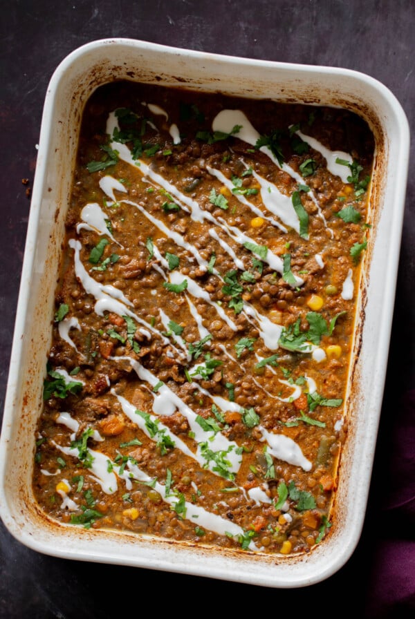 Konkani curry dal casserole topped with coconut cream, cilantro, and pepper flakes in the baking pan