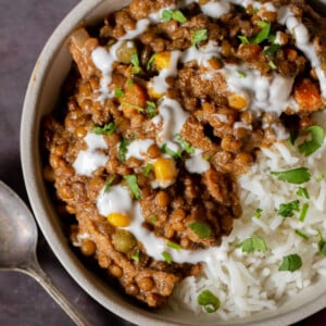 bowl of baked Konkani curry topped with coconut cream, cilantro, and pepper flakes