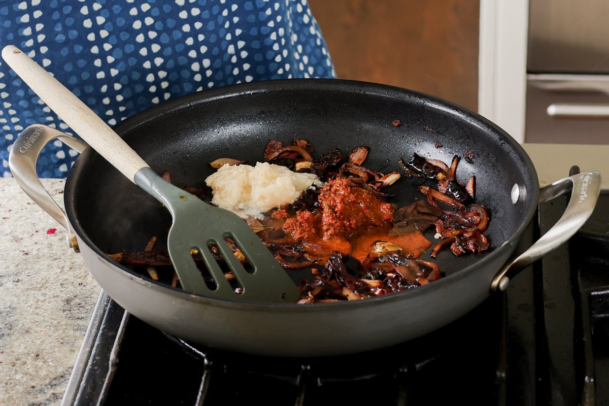 adding ginger garlic paste and ground spices to the pan