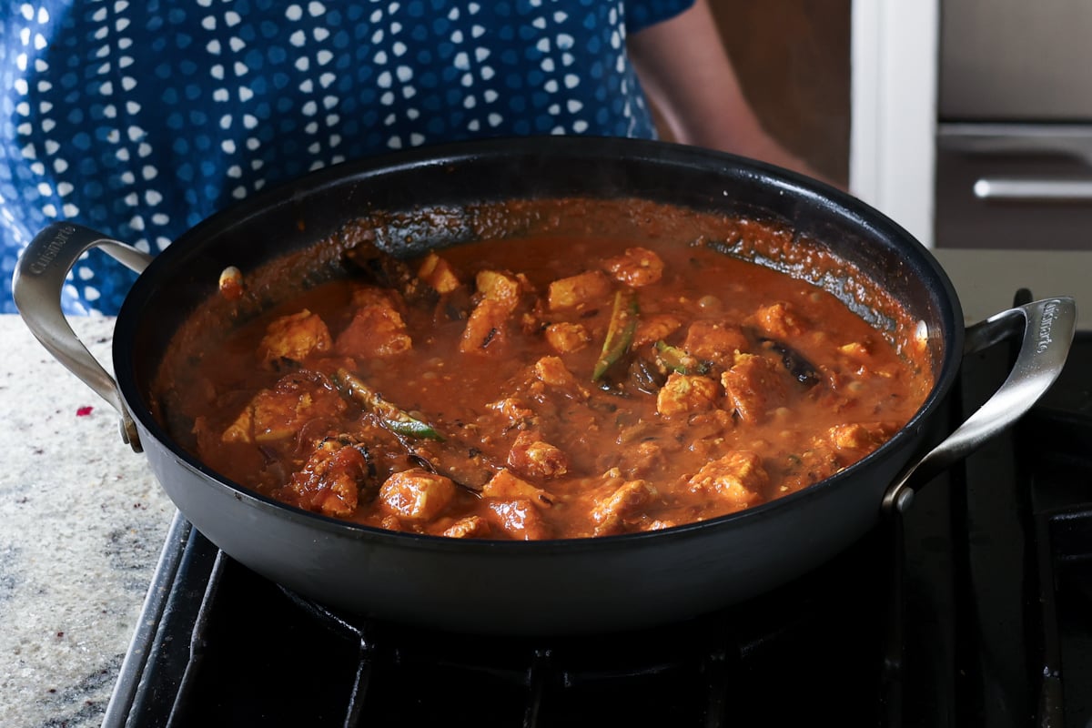 tofu and chilis mixed into kosha mangsho sauce in the pan