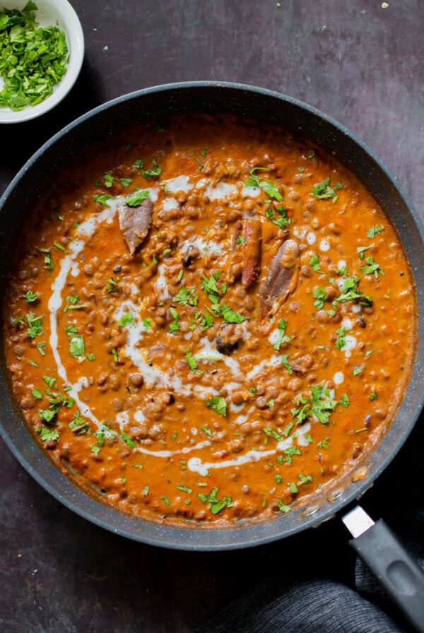 dal lasooni in the pan with cilantro and a swirl of cream