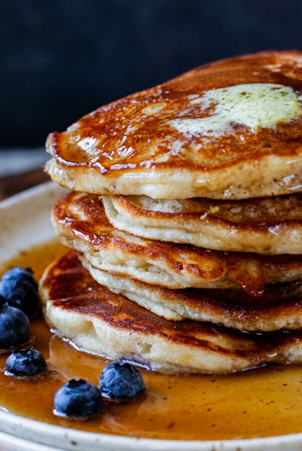 close-up of a stack of gluten-free lemon blueberry pancakes on a plate with blueberries