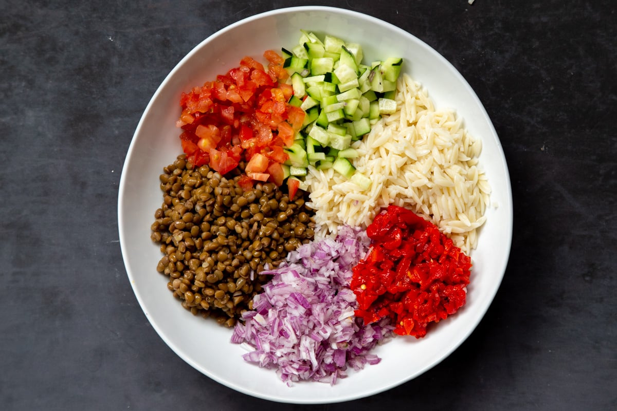 all lentil farrot salad ingredients arranged in a white salad bowl