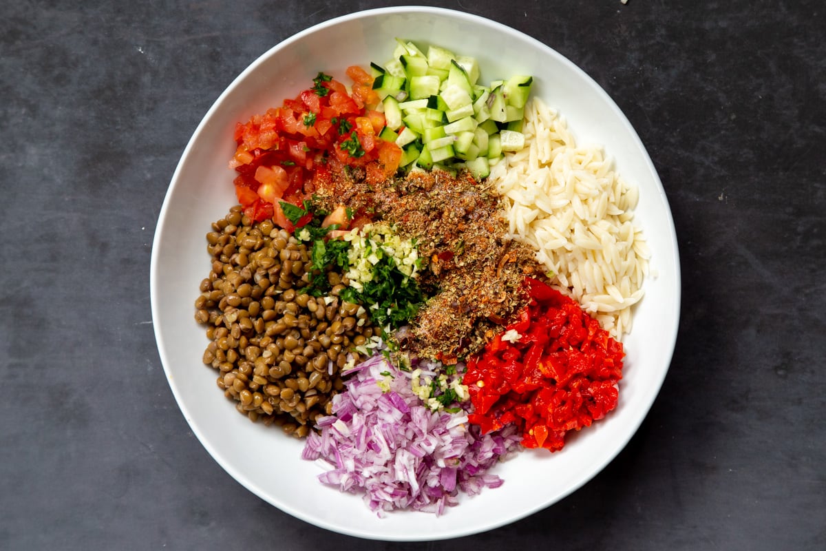 spices and dressing being added to lentil farro salad