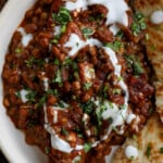 lentils vindaloo on a plate with toppings and naan