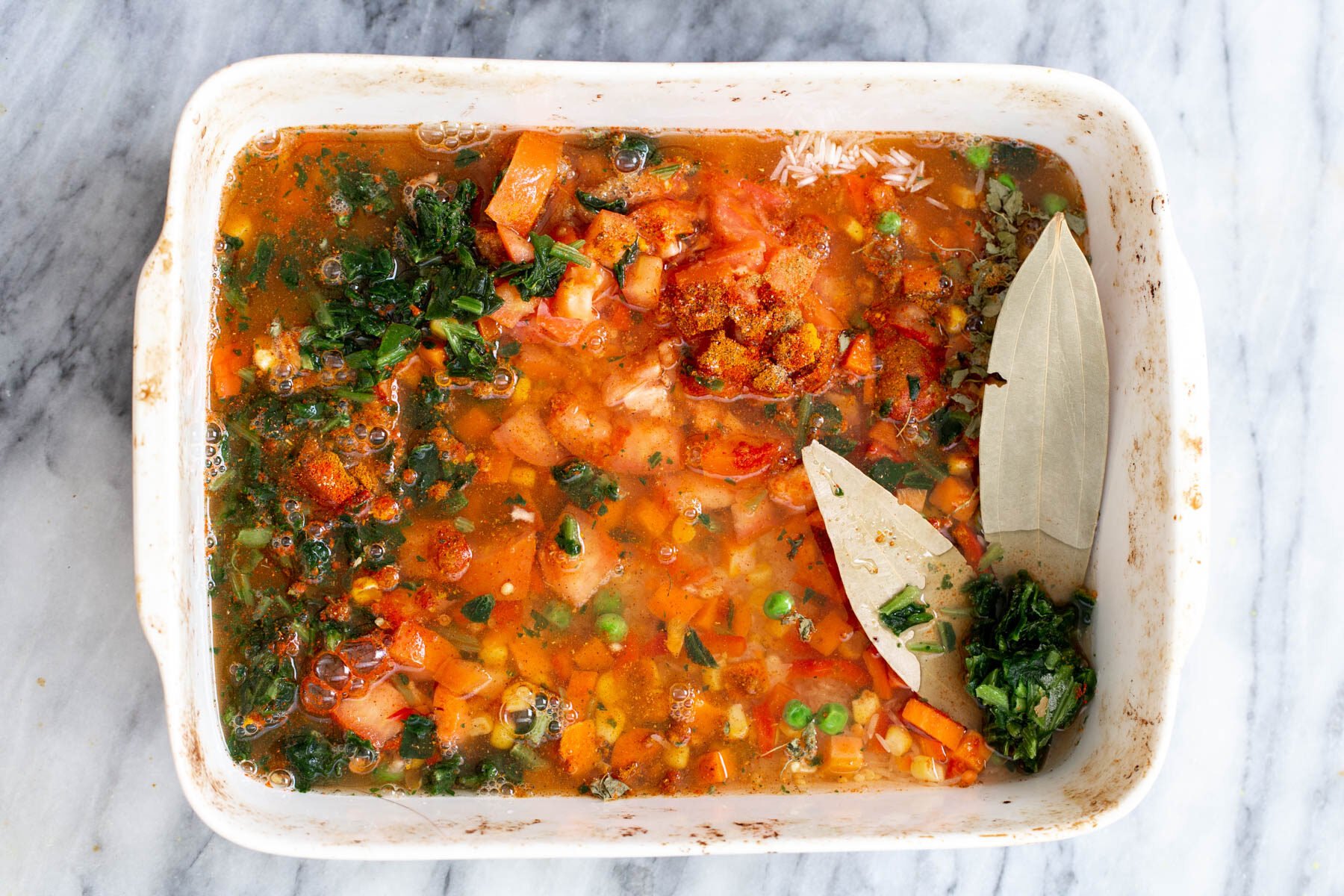 rice and vegetables cooking in a casserole dish 