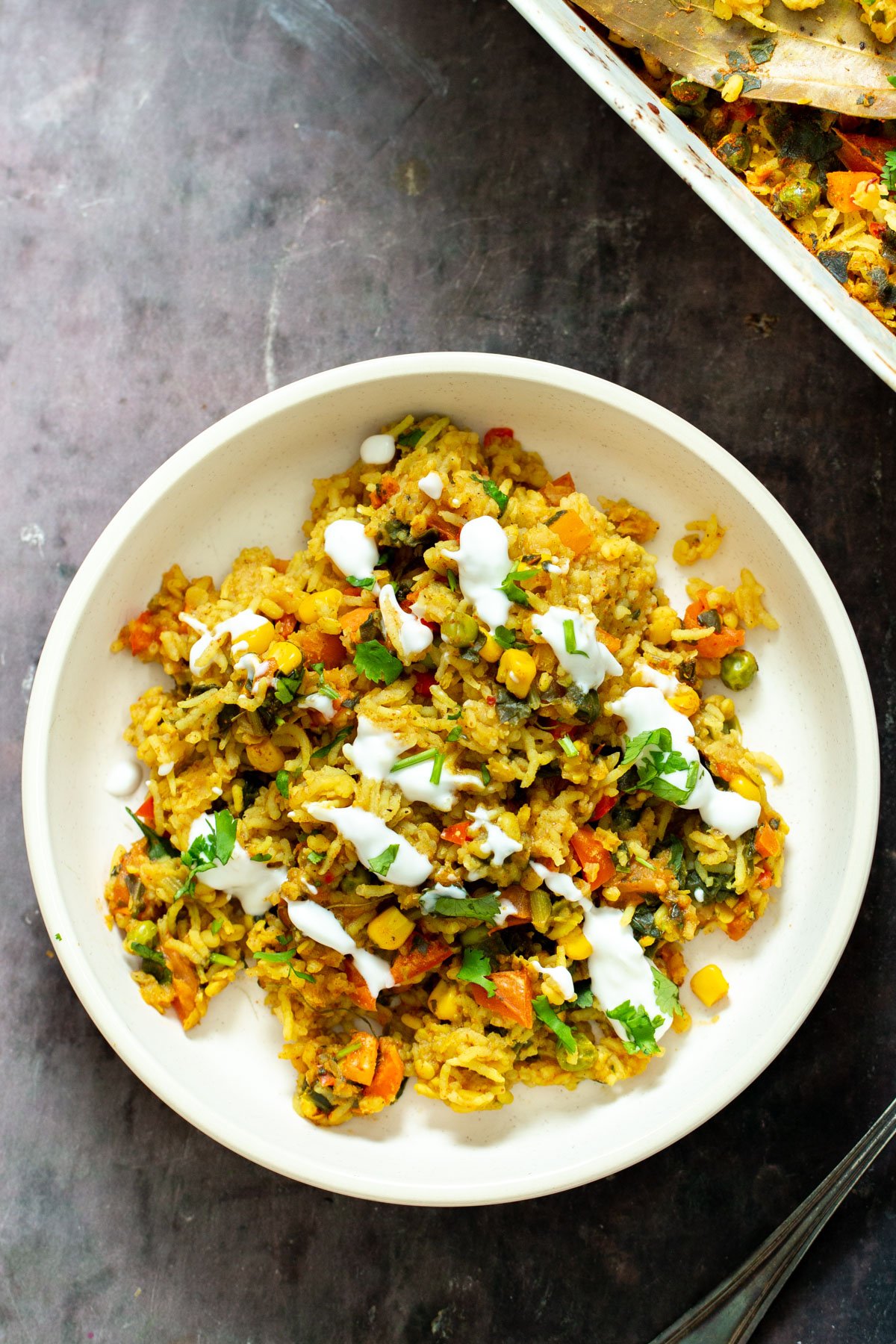 a serving of baked lentil rice casserole drizzled with vegan yogurt