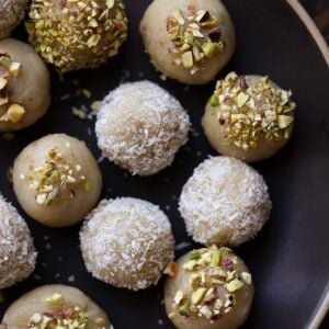 plate of vegan malai ladoo topped with coconut and pistachio